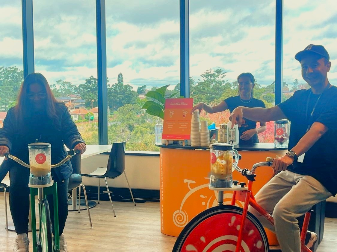 smiling corporate employees having fun in a team building activity with bike n blend and smoothies