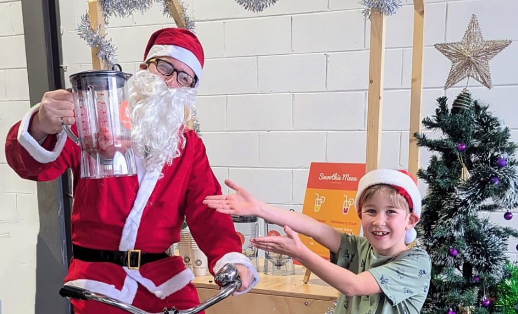 Santa and child showing off their freshly made healthy smoothie - no more boring waiting for santa photos!