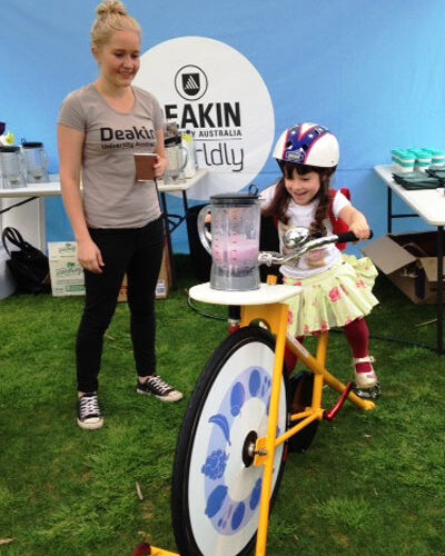 Bike n Blend activation on-capmus at Deakin University, with a young girl smiling and riding the smoothie bike